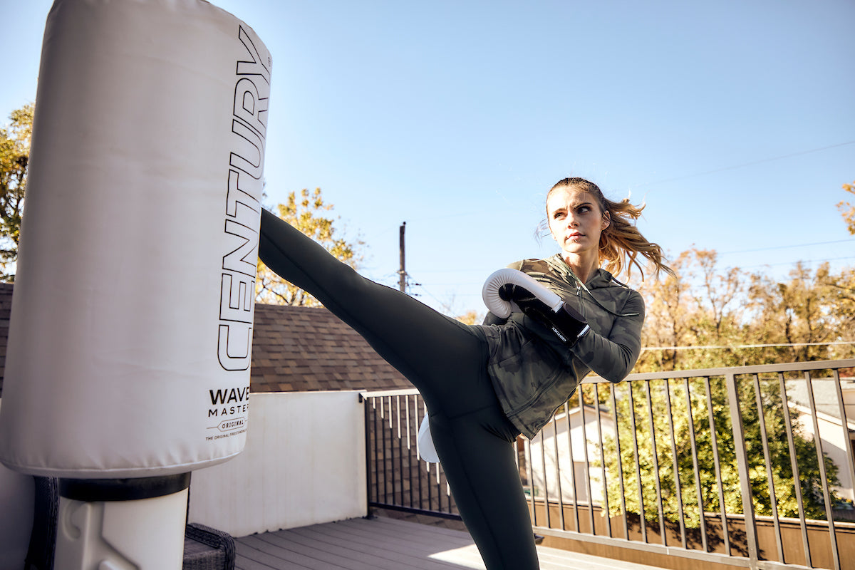 Woman wearing gloves and kicking bag