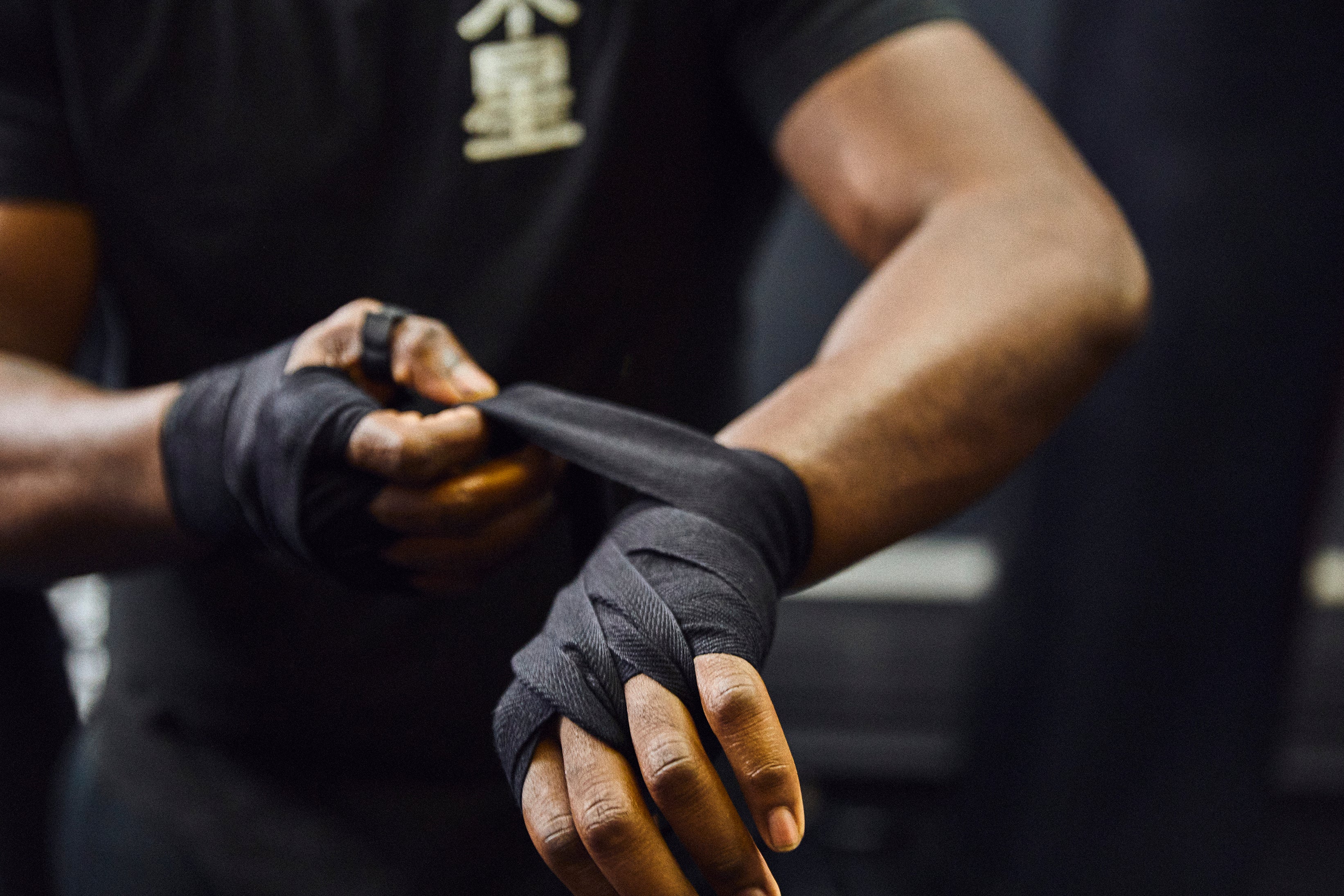 close-up of a person wrapping their hands with boxing wraps in a gym setting