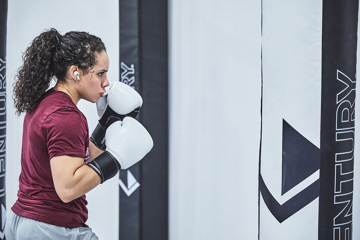 Woman in gloves hitting bag