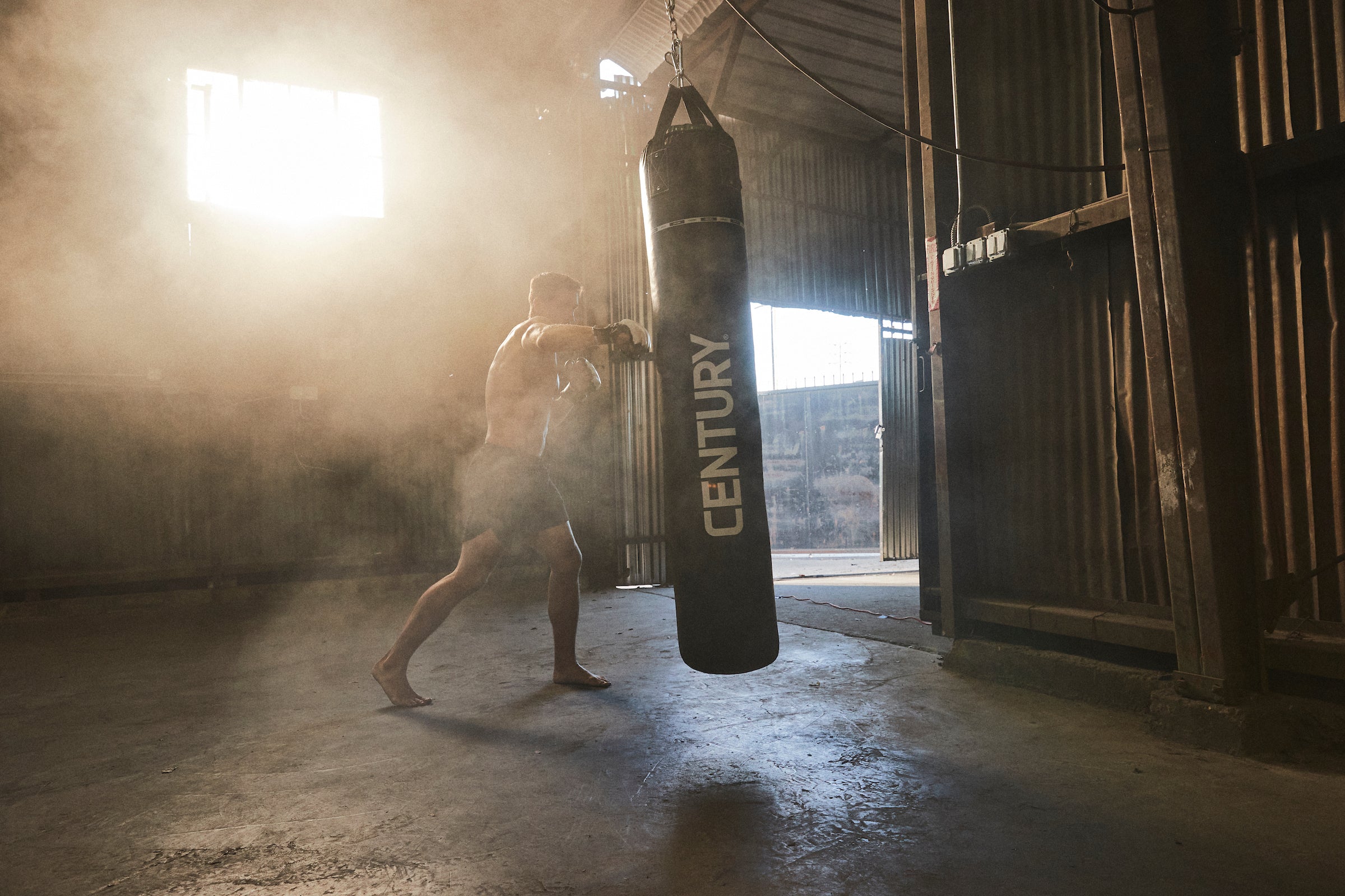 Man in foggy gym hitting bag