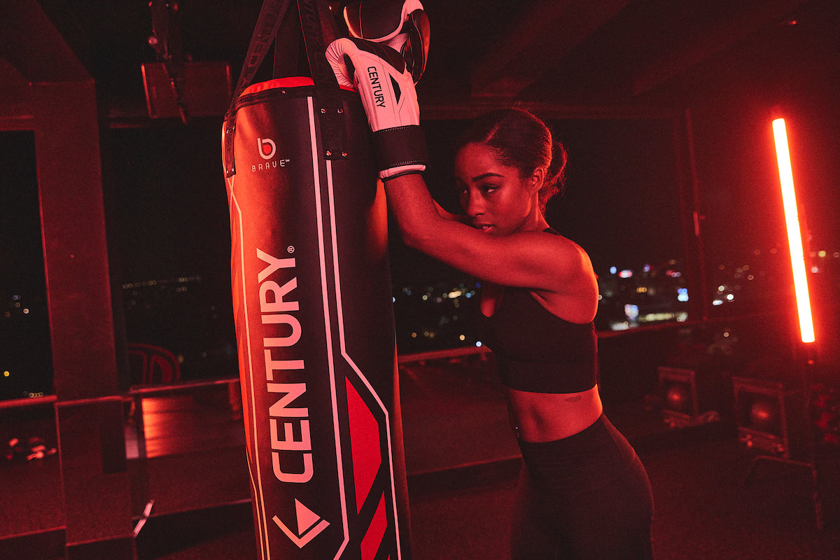 Woman wearing gloves training with bag