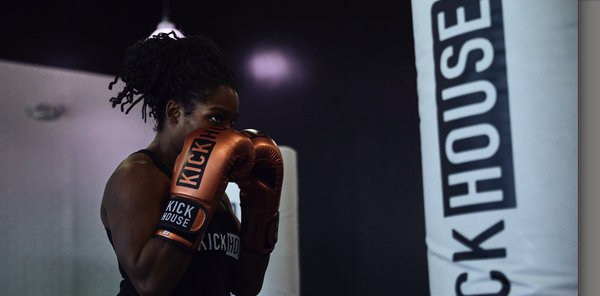 woman wearing boxing gloves and facing a punching bag