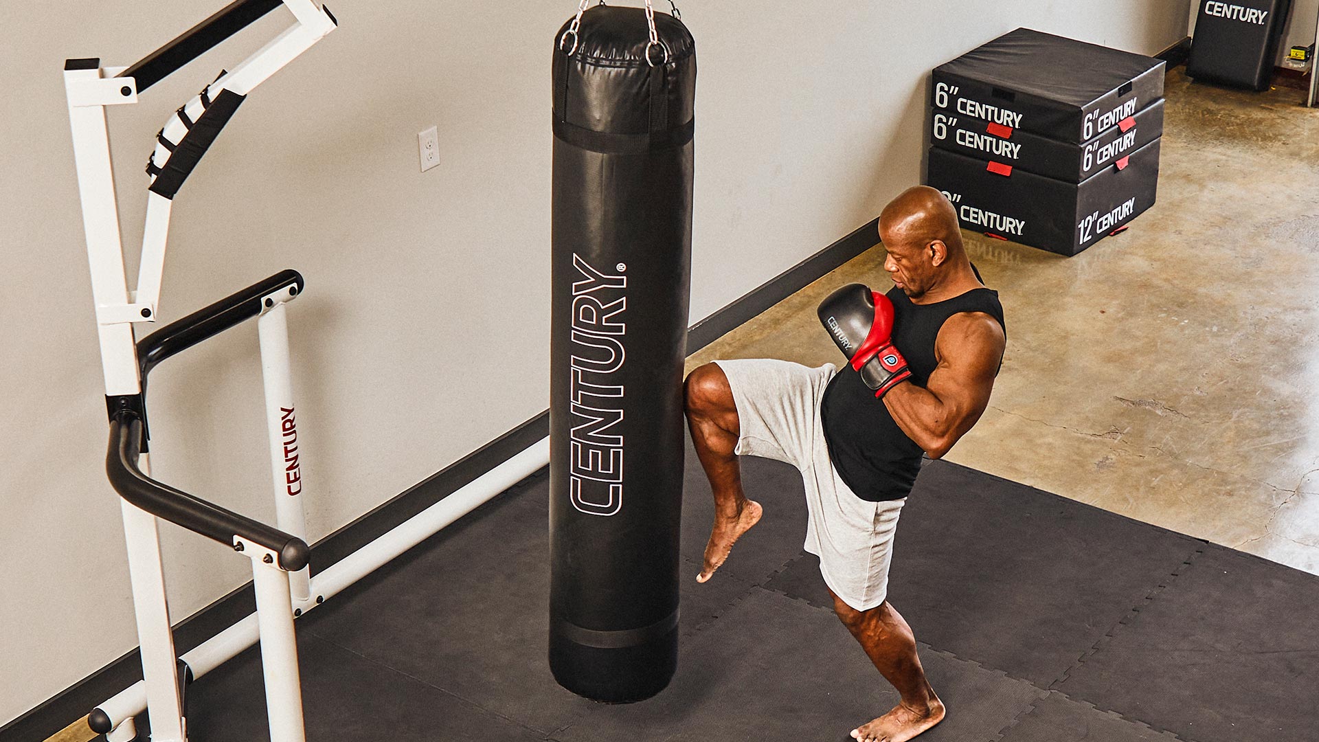 man kneeing century's mauy thai hanging bag on a bag stand