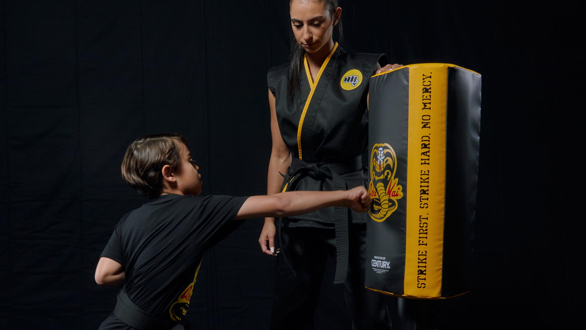 woman instructing student using century's cobra kai wavemaster freestanding bag