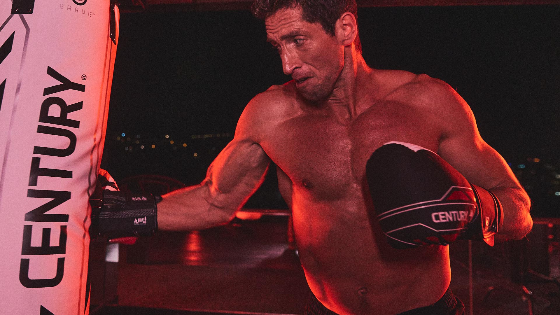 Man punching century hanging bag wearing kickboxing gloves