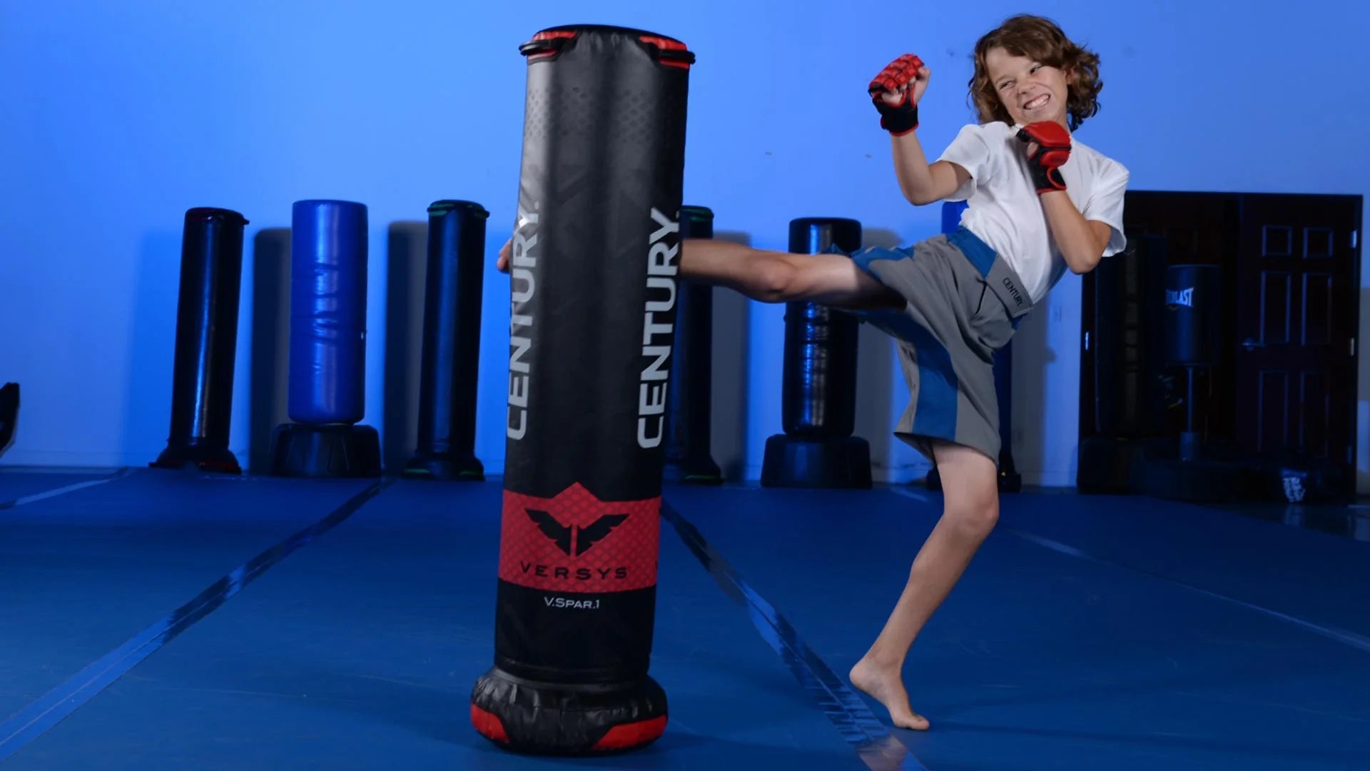 kid kicking freestanding bag v.spar.1 while wearing mma gloves