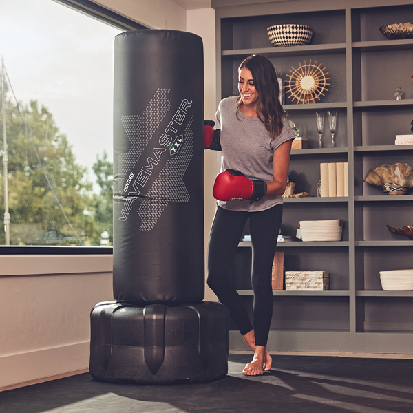 Girl posing with boxing gloves and black wavemaster punching bag