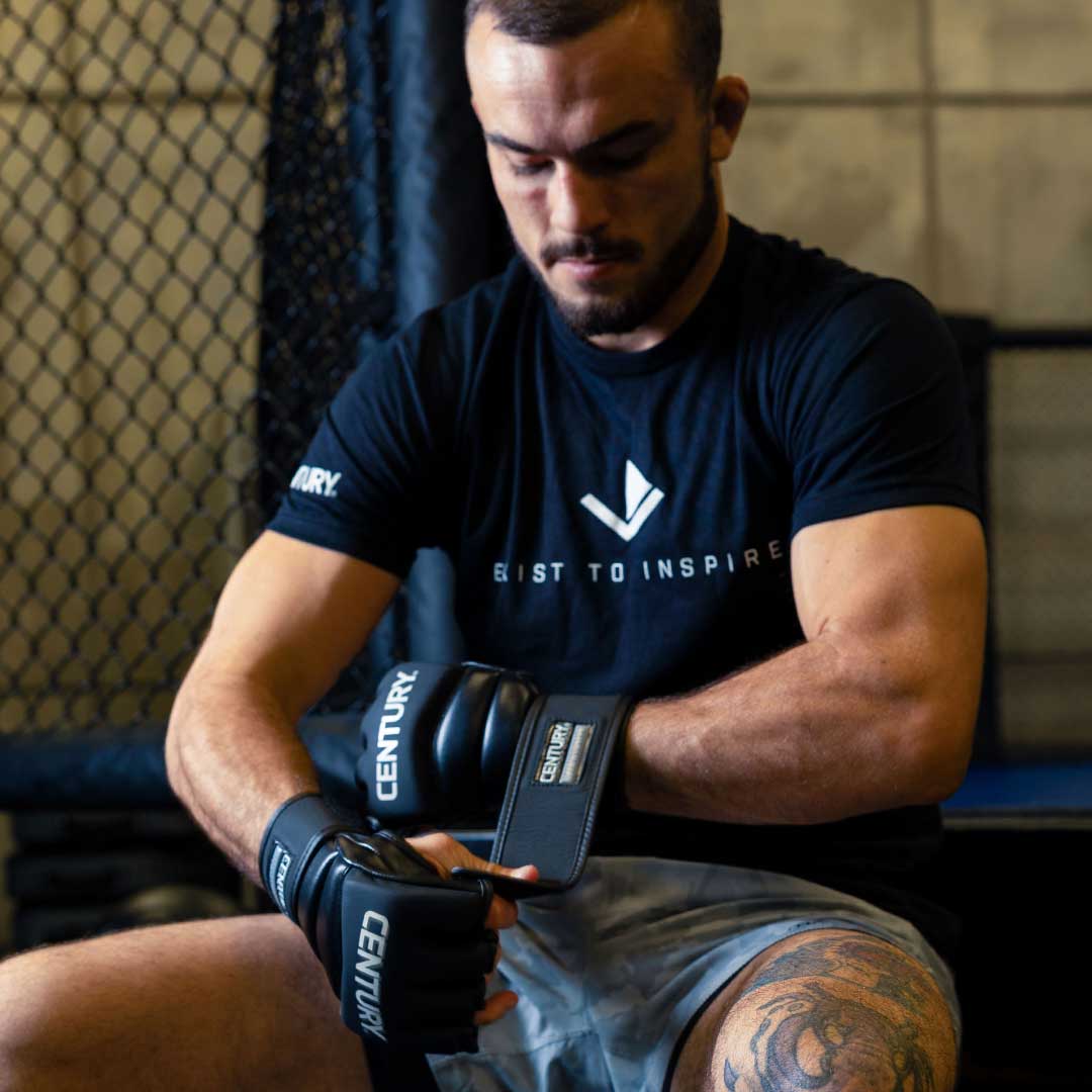 man in black century tshirt putting on black century gloves