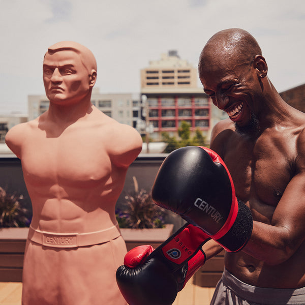 Man putting gloves on next to BOB punching bag